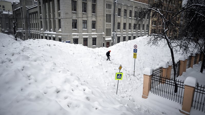 A pedestrian crosses a street used for temporary snow storage in Moscow today