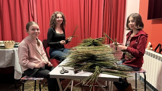 Nan, Nellie and Eppie Fortune sit around a table together making St Brigid's crosses