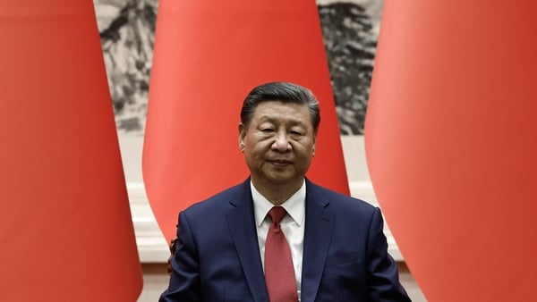 Chinese President Xi Jinping sits in front of his nation's flags.