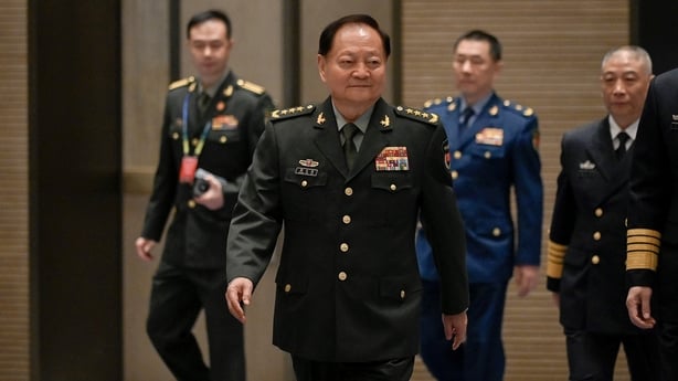 Zhang Youxia in military uniform walking through a hall.