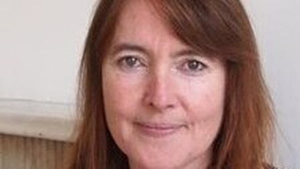 writer Catherine Ann Cullen, against a white backdrop with marble mantlepiece in background