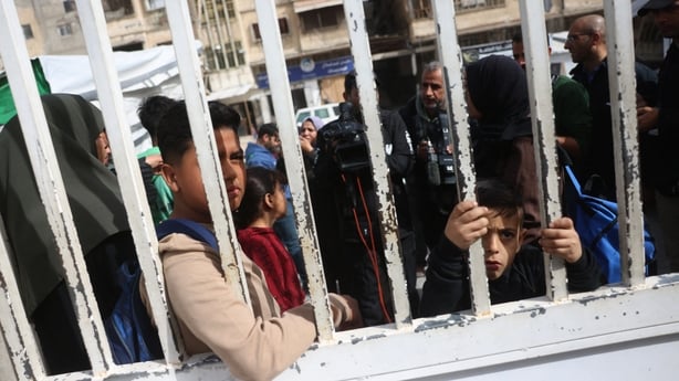Palestinian youth and their guardians wait in the grounds of the Red Crescent Hospital to be evacuated from the Gaza