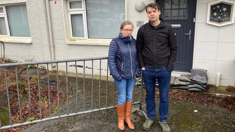 A man and a woman stand in front of a house