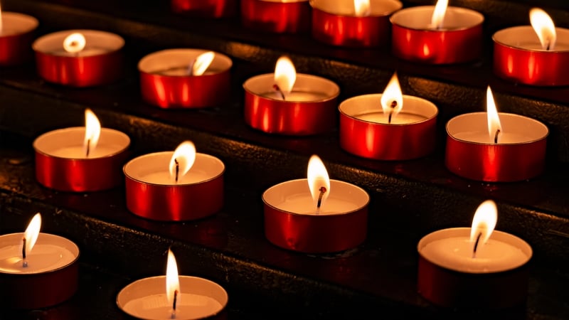 Collection of lit prayer candles against a dark backdrop.
