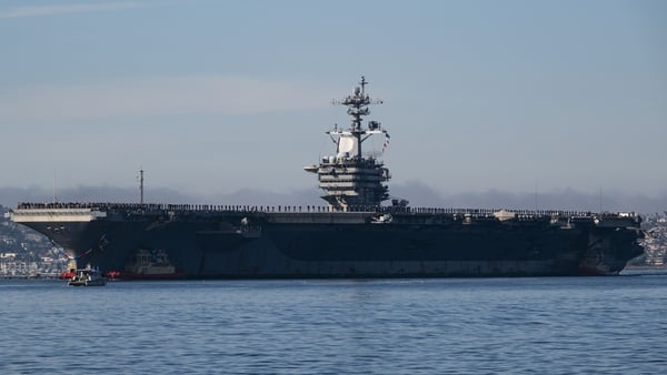 SAN DIEGO, CALIFORNIA - DECEMBER 20: Sailors and marines man the rail as the U.S. Navy Nimitz-class aircraft carrier USS Abraham Lincoln (CVN 72) is guided by tugboats in San Diego Bay as it returns to its homeport of Naval Air Station North Island after