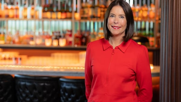 Image of a business woman with rows of bottles of alcohol behind her