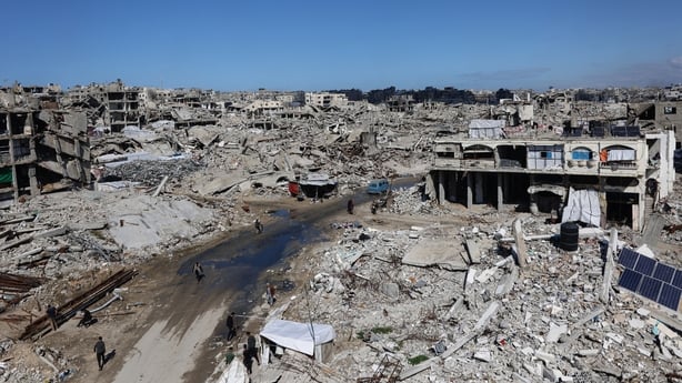 Palestinians make their way through the rublle of destroyed buildings in the Sheikh Radwan neighborhood of Gaza City