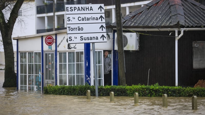 A man stands at the door of his establishment surrounded by water in Alcacer do Sal, south of Portugal - GETTY