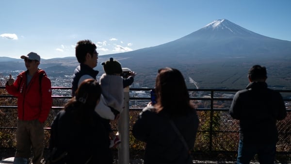 Chinese tourists pose for photographs in front of Mount Fuji