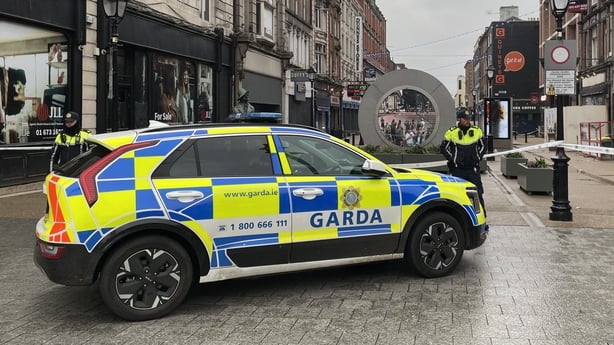 a garda car with a garda standing beside it on dublin's north earl street