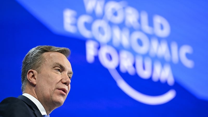 Man speaking on a stage with WEF signage behind him