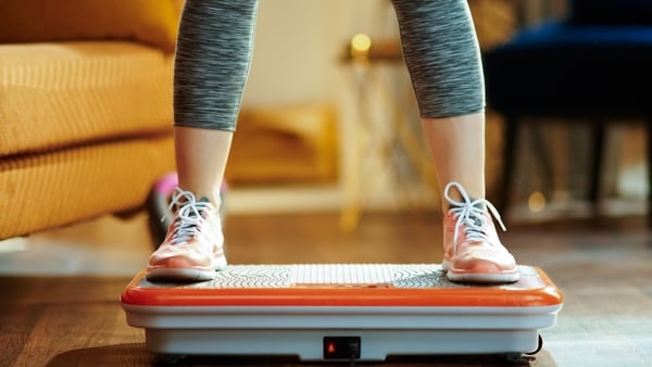 Closeup on young woman in fitness clothes in the modern house training using vibration power plate.