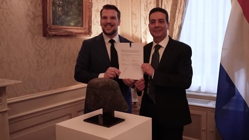 Two men stand behind an egyptian artefact displayed on a table