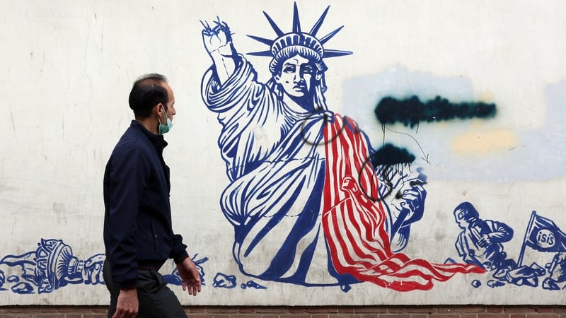 A man walks past a mural depicting the US Statue of Liberty with the torch-bearing arm broken, painted on the outer walls of the former US embassy, in Tehran