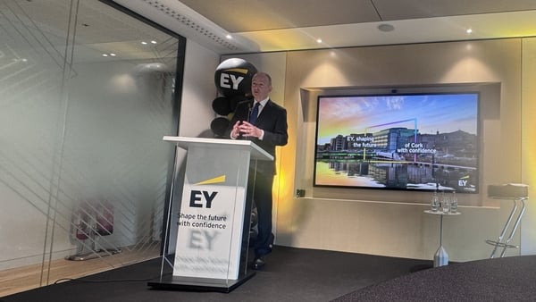 The Taoiseach Micheál Martin stands at a podium in front of an image of the new EY expanded offices in Cork