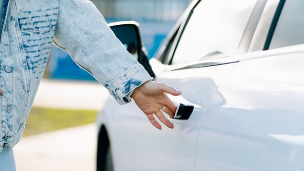 Woman's hand reaching for a car door handle