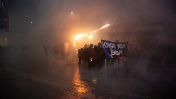Protesters advance behind a banner during clashes in Milan