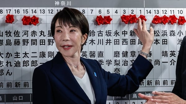 Sanae Takaichi places a red paper rose on the name of an elected candidate at the Liberal Democratic Party HQ.