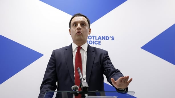 Scottish Labour leader Anas Sarwar standing in front of Sta Andrew's cross with a logo 