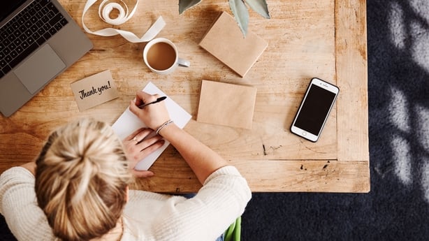 Overhead Shot Looking Down On Woman Writing In Generic Thank You Card