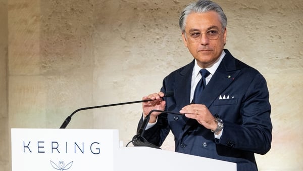 Business man stands at a podium with the Kering logo on it