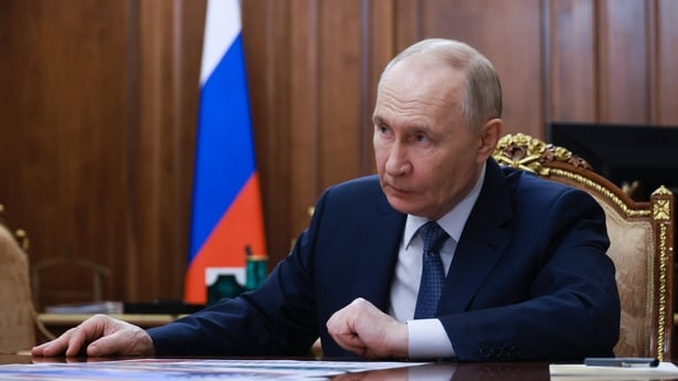 Russia's President Vladimir Putin sitting at a desk