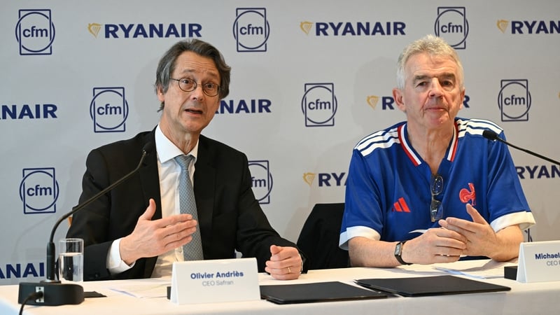 Two business men seated at a press conference with Ryanair and CFM signage behind them