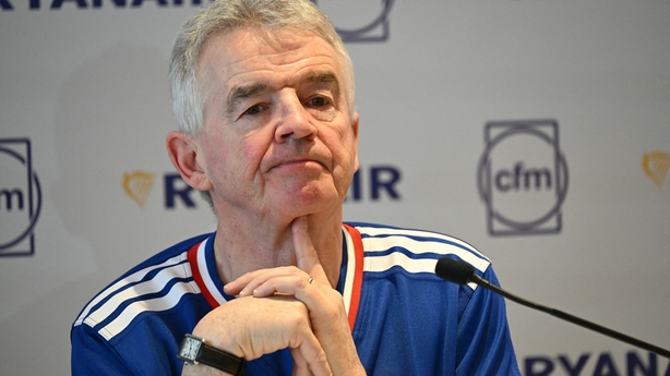 Business man in a rugby jersey sits at a press conference 