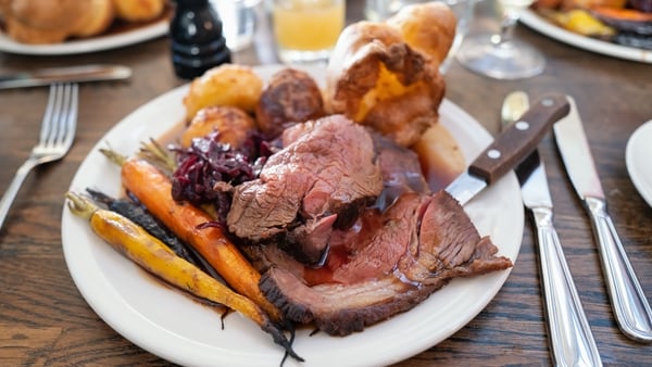 Roast beef on a white plate with roast potatoes and Yorkshire pudding with vegetables in a restaurant.