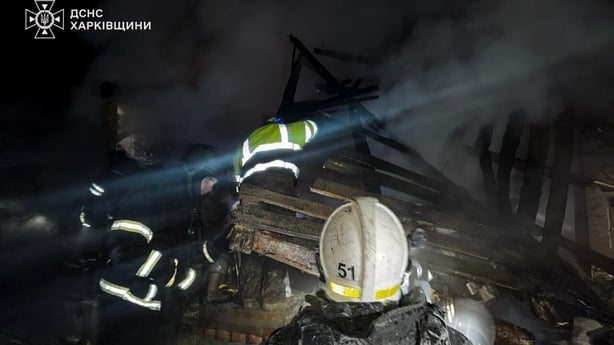 People dressed in hi vis clothing and helmets assess destruction