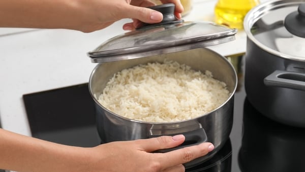 Woman cooking rice on stove in kitchen