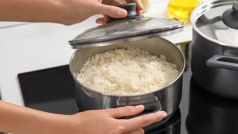 Woman cooking rice on stove in kitchen