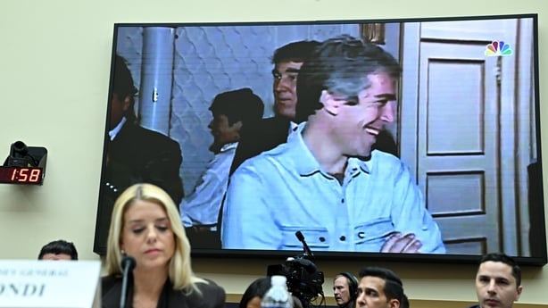 An image of US President Donald Trump and deceased financier Jeffrey Epstein is displayed behind Pam Bondi