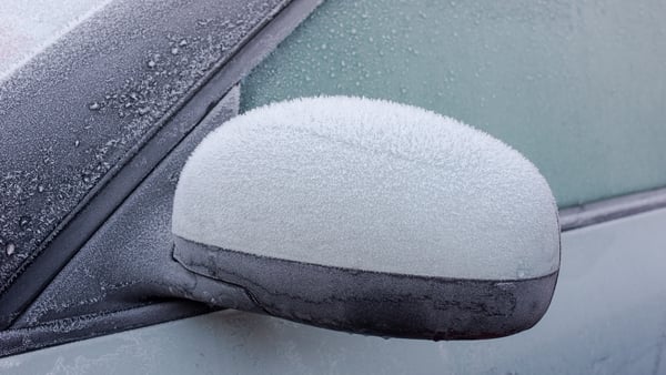 Ice on a car wing mirror, with the frozen car behind