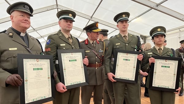 Five soldiers stand in a line with four of them holding an A4 size document