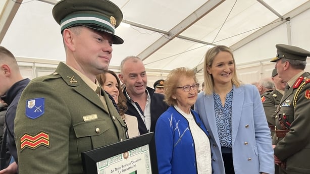 a soldier is pictured alongside a group of people posing for a photograph