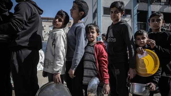 GAZA CITY, GAZA - FEBRUARY 12: Children line up as a charity distributes food to displaced Palestinians in the Rimal neighborhood of Gaza City as the food shortage continues due to Israel's blockade and restrictions on aid entering the Gaza Strip on Febru