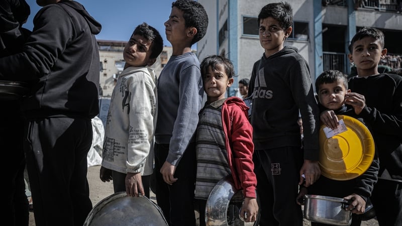GAZA CITY, GAZA - FEBRUARY 12: Children line up as a charity distributes food to displaced Palestinians in the Rimal neighborhood of Gaza City as the food shortage continues due to Israel's blockade and restrictions on aid entering the Gaza Strip on Febru