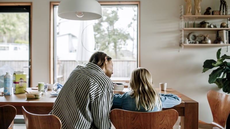 A woman sits at a table with a young child