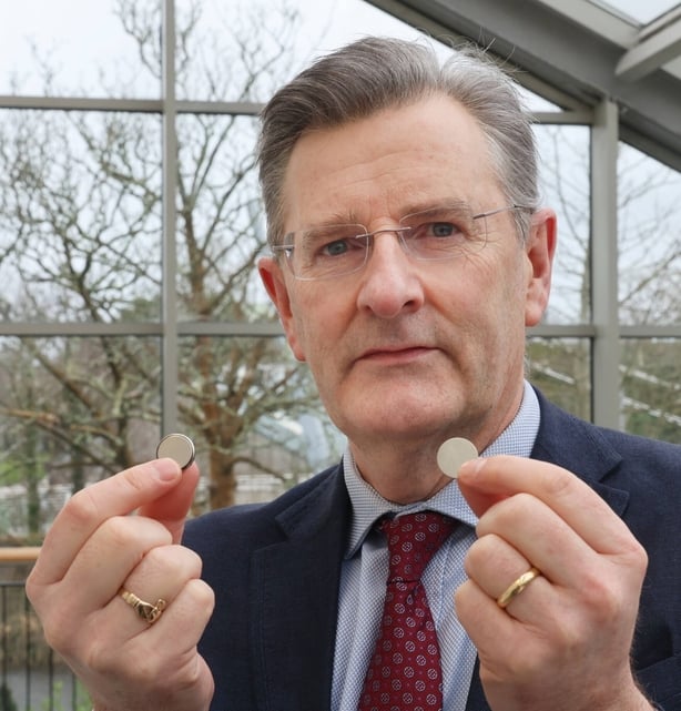 Ivan Keogh holding two button batteries