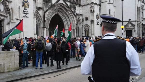 A police officer observes protesters gathered outside the UK High Court