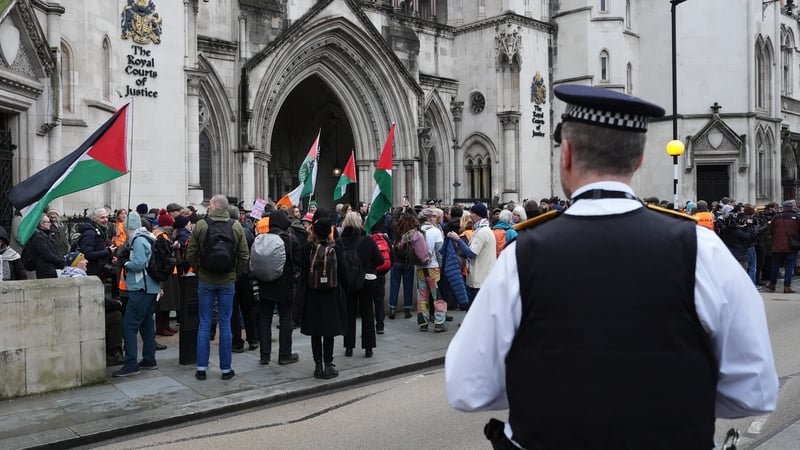 A police officer observes protesters gathered outside the UK High Court