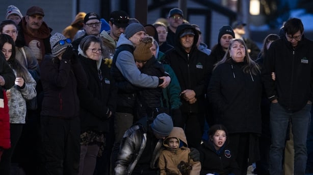 People comfort each other at a vigil 