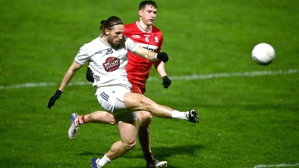 Kildare's Neil Flynn kicks a point despite the attention of Derry defender Gareth McKinless