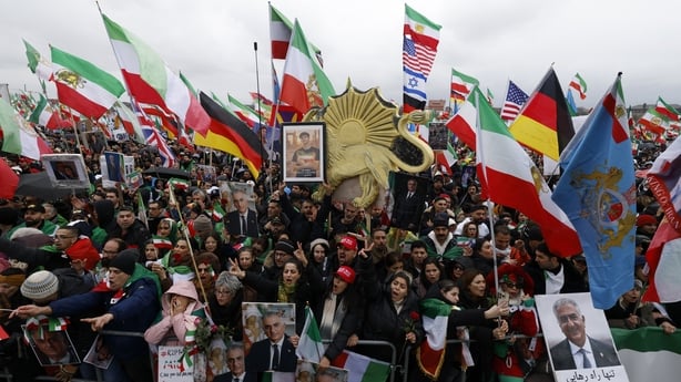 Participants hold up flags, among them the historic Iranian "Lion and Sun" national flag, as well as posters depicting Iran's former crown prince and now key opposition figure Reza Pahlavi during a demonstration of the Iranian opposition