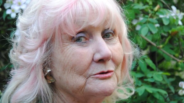 writer Anne Le Marquand Hartigan, looking sideways to camera, shrubbery in background