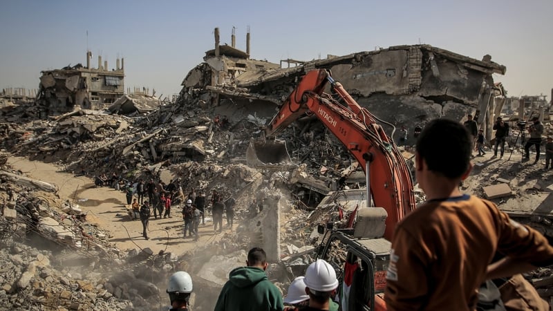 Civil defense teams, in coordination with officials from the International Committee of the Red Cross (ICRC), use heavy machinery to search the rubble of a destroyed building to recover bodies