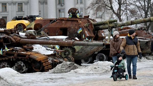 A couple and a boy on a bicycle walk in the open air exhibition of destroyed Russian military equipment in Kyiv
