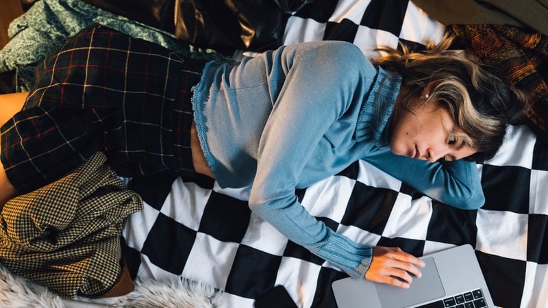 woman lying in bed looking at laptop
