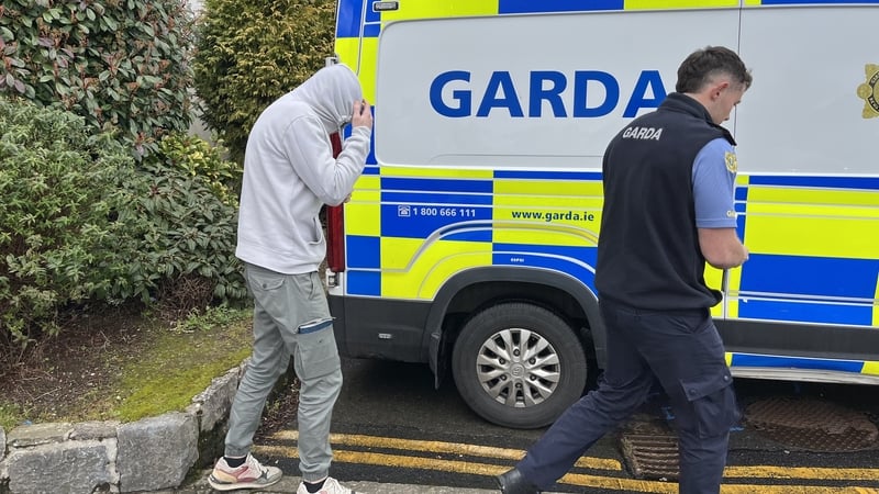 Seán Tyrrell covers his face with a hood beside a garda van